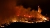 A helicopter drops water over the Thompson wildfire as firefighters continue battling fire into the night near Oroville, California, July 2, 2024. 