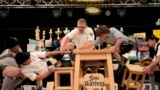 Men dressed in traditional clothes try to pull the opponent over the table at the German Championships in Fingerhakeln or finger wrestling, in Bernbeuren, Germany, May 12, 2024. 