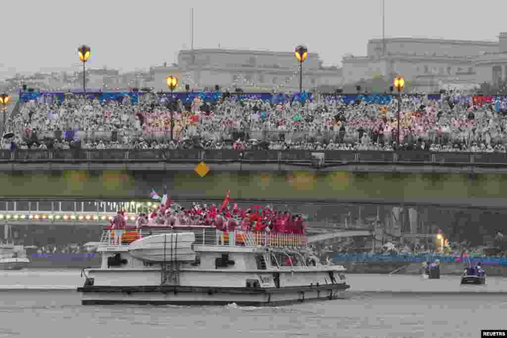 China&#39;s and Canada&#39;s teams move down the Seine as spectators look on in the rain in Paris during the opening ceremony of the 2024 Summer Olympics, July 26, 2024.
