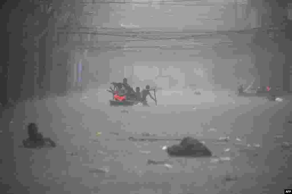 Rescuers paddle their boats along a flooded street in Manila, Philippines amid heavy rains brought by Typhoon Gaemi. (Photo by Ted ALJIBE / AFP)