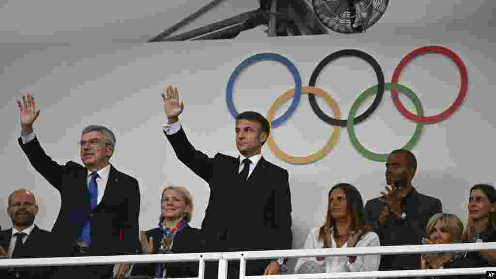 France's President Emmanuel Macron, center, and IOC President Thomas Bach, left, wave as they arrive to attend the opening ceremony for the 2024 Summer Olympics in Paris, July 26, 2024.