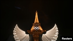 Эйфелева башня с подсветкой крыльев на переднем плане после церемонии открытия Олимпийских игр 2024 года в Париже, 26 июля 2024 года.