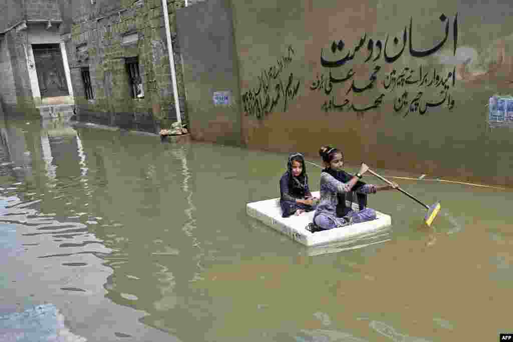 Girls use a temporary raft across a flooded street after heavy monsoon rains in Karachi, Pakistan.