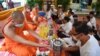 People offer food to Buddhist monks during the Pchum Ben festival (Festival of Death) at a pagoda in Phnom Penh on September 3, 2020. (Photo by TANG CHHIN Sothy / AFP)