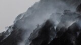 FILE - A waste collector climbs down while looking for recyclable materials as smoke billows from burning garbage at the Bhalswa landfill site on World Environment Day in New Delhi, India, June 5, 2022. (REUTERS/Anushree Fadnavis)