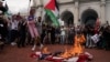 Bendera AS dibakar sementara seorang demonstran pro-Palestina memegang patung Perdana Menteri Israel Benjamin Netanyahu, selama aksi protes anti-Netanyahu di luar Union Station di Washington, DC hari Rabu (24/7). 