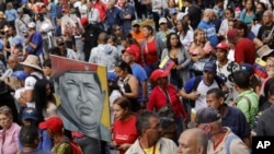 Partidarios del gobierno sostienen una pintura del fallecido presidente venezolano Hugo Chávez, durante un evento que marca el aniversario del golpe de 1958, en Caracas, Venezuela, el martes 23 de enero de 2024. (Foto AP/Jesús Vargas)