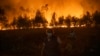 People stand watching the progression of a wildfire at Veiga village in Agueda, Aveiro, Sept. 17, 2024. Stifling heat and strong winds have fanned a spate of forest fires across the north and centre of the country that have killed seven people dead since the weekend.