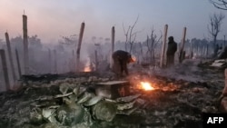 Izbjeglice Rohingya gledaju kroz ruševine svojih kuća izgorenih u razornom požaru u kampu Ukhia, Cox's Bazaar u ranim satima 7. januara 2024.