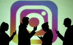 In this file photo, silhouettes of mobile users are seen next to a screen projection of the Instagram logo in this picture illustration taken March 28, 2018. (REUTERS/Dado Ruvic/Illustration/File Photo)