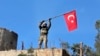 FILE -- In this Sunday, Jan. 28, 2018 file photo, a soldier waves a Turkish flag as Turkish troops secure Bursayah hill, near the Kurdish-held enclave of Afrin.