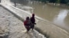 FILE - Residents walk as they leave the flooded areas in Maiduguri, Nigeria, Sept. 15, 2024. Nigeria is grappling with severe floods in northeastern Borno state where a dam burst its walls after heavy rains. 