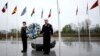 (FILE) Two military personnel stand underneath the flags of NATO alliance members during wreath laying ceremony at NATO headquarters in Brussels, Thursday, April 4, 2024.