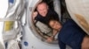 Астронавты Буч Уилмор (слева) и Суни Уильямс позируют в тамбуре между портом модуля Международной космической станции и кораблем Starliner 13 июня 2024 года. (NASA via AP)