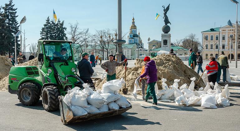 На фото: харьковчане обкладывают памятники мешками с песком. 