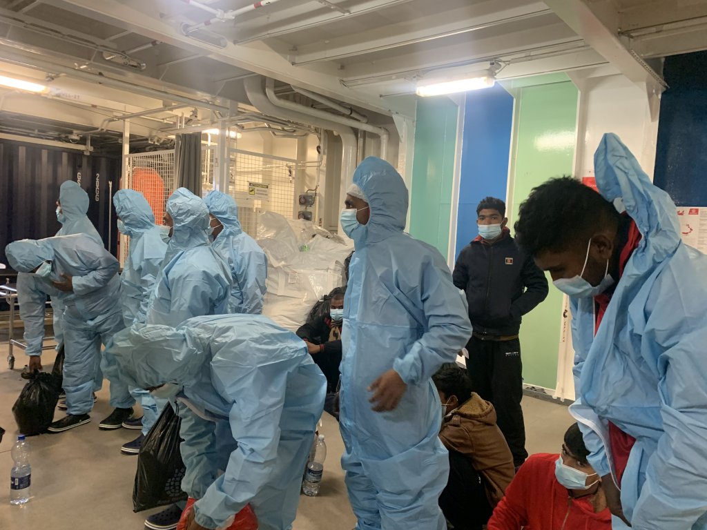 تم عزل المهاجرين المصابين بالجرب عبر إلباسهم بدلات زرقاء قبل مغادرة السفينة في رافينا 