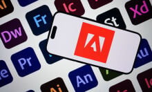 Adobe logo on a smartphone screen against the backdrop of Adobe program logos 