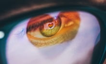 Woman with a rainbow heart reflected in her eyes and glasses.