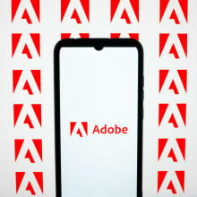 adobe logo on a smartphone against a background of adobe icons