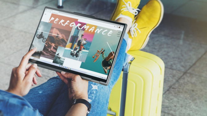 Laptop over crossed legs at an airport, perched on top of a rollaway luggage