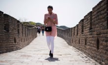 Woman holding a smart phone walks along the Great Wall in Mutianyu