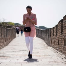 Woman holding a smart phone walks along the Great Wall in Mutianyu