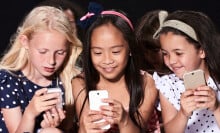A group of three young girls using smartphones.