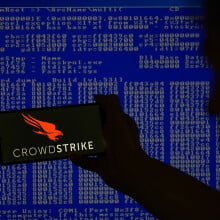 crowdstrike logo on phone in front of screen of code