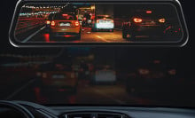 A rearview mirror showing cars driving at night. 