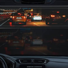 A rearview mirror showing cars driving at night. 