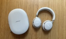 A pair of Bose QuietComfort Ultra headphones with case on wood surface