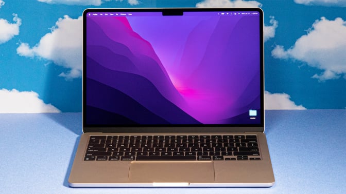 2022 MacBook Air M2 laptop open against a blue backdrop with cloud patterns