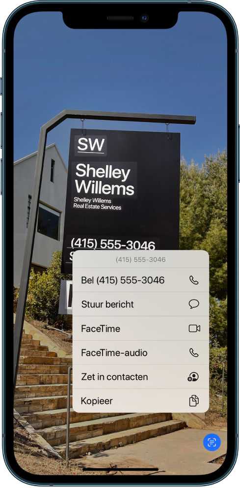 Een foto is schermvullend geopend. In de foto is een teken te zien met tekst en een telefoonnummer. Het telefoonnummer is geselecteerd en de volgende opties zijn beschikbaar op het scherm: 'Bel', 'Stuur bericht', 'FaceTime', 'FaceTime-audio', 'Zet in contacten' en 'Kopieer'.