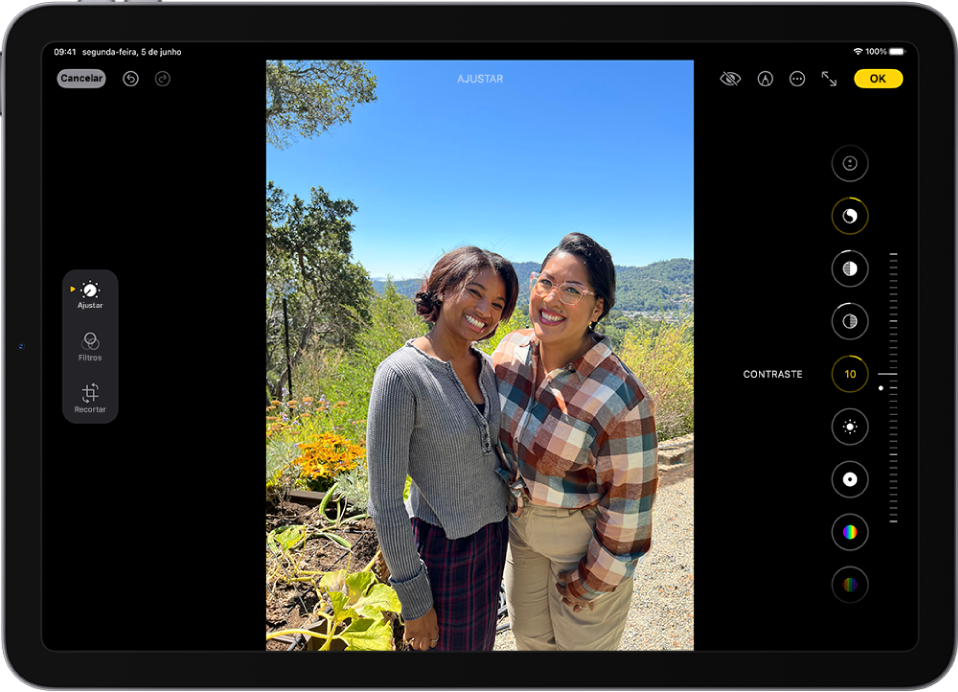 O ecrã de edição da aplicação Fotografias com uma fotografia ao centro. No lado esquerdo da fotografia encontram‑se os botões Ajustar, Filtros e Recortar; o botão Ajustar está selecionado. À direita da fotografia encontram‑se botões para efeitos de edição e um nivelador para ajustar cada nível de efeito.