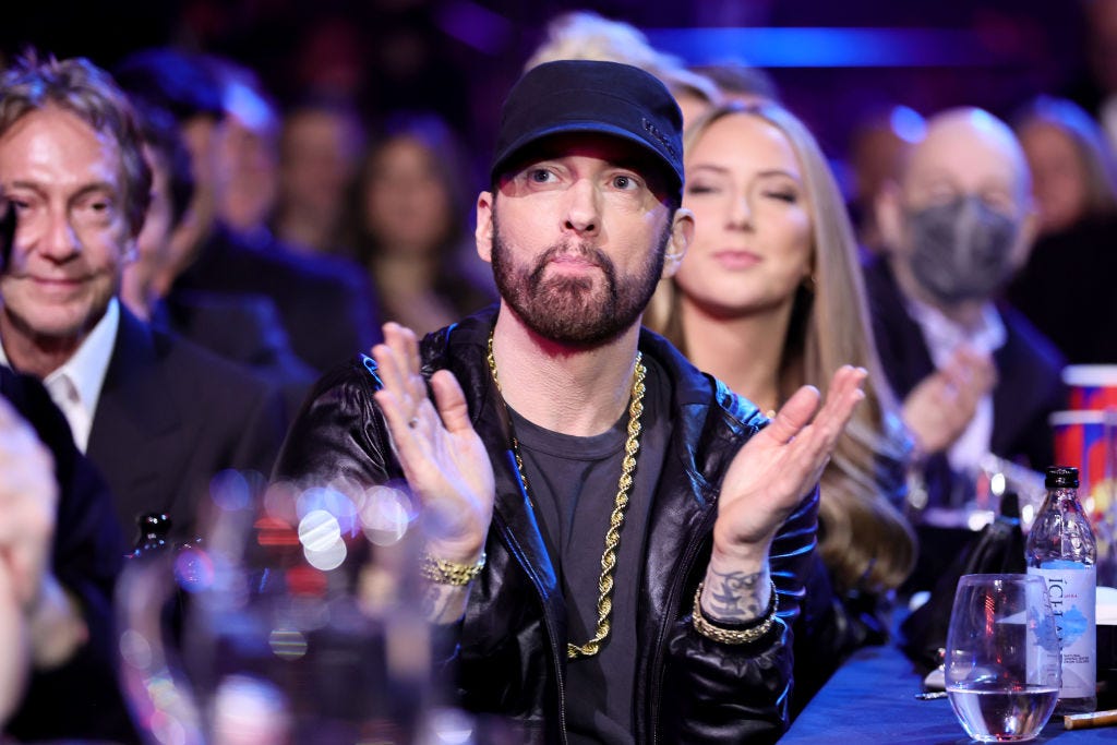 eminem clapping his hands while looking up sitting at a table