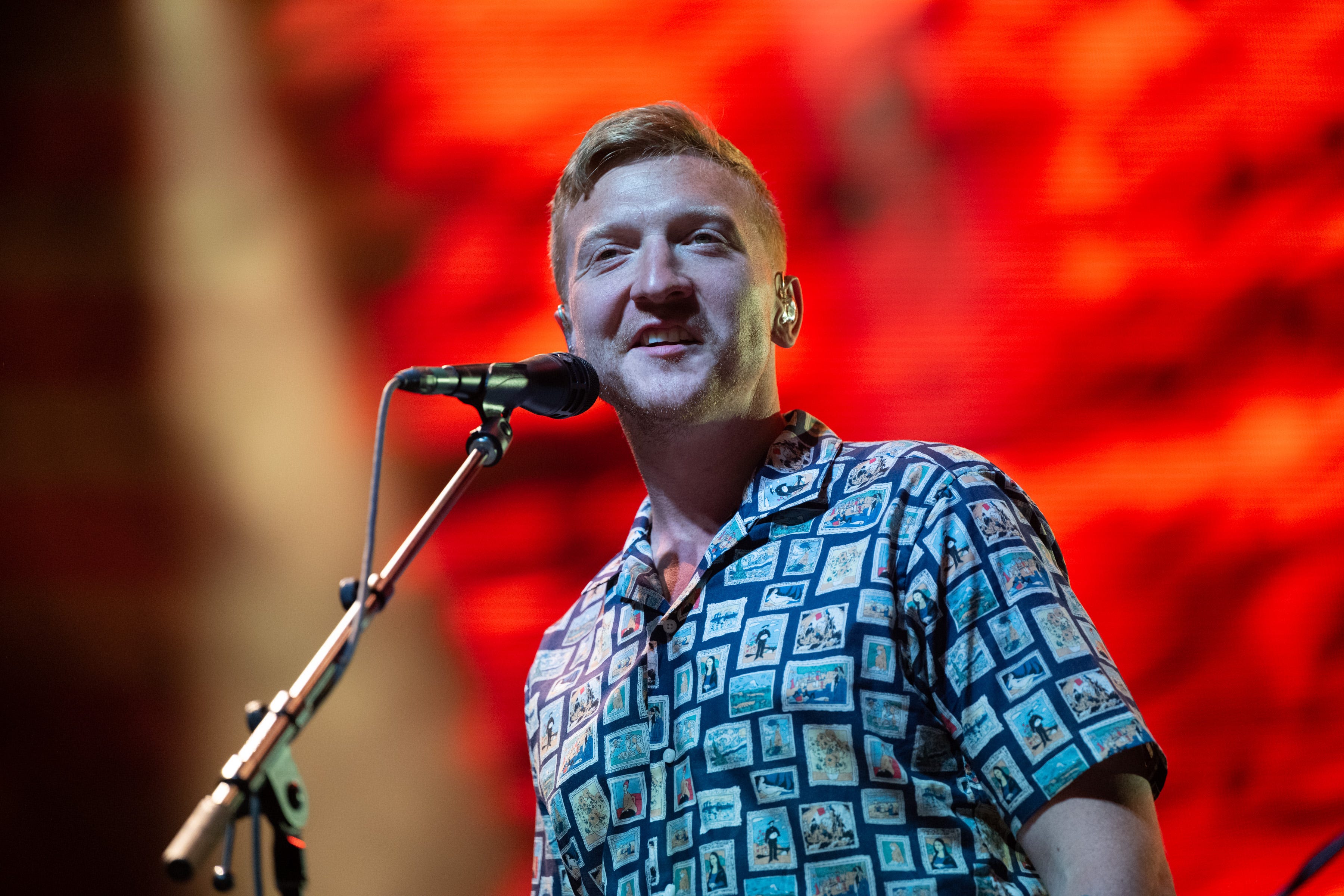 tyler childers smiling as he looks out into a crowd with a red background