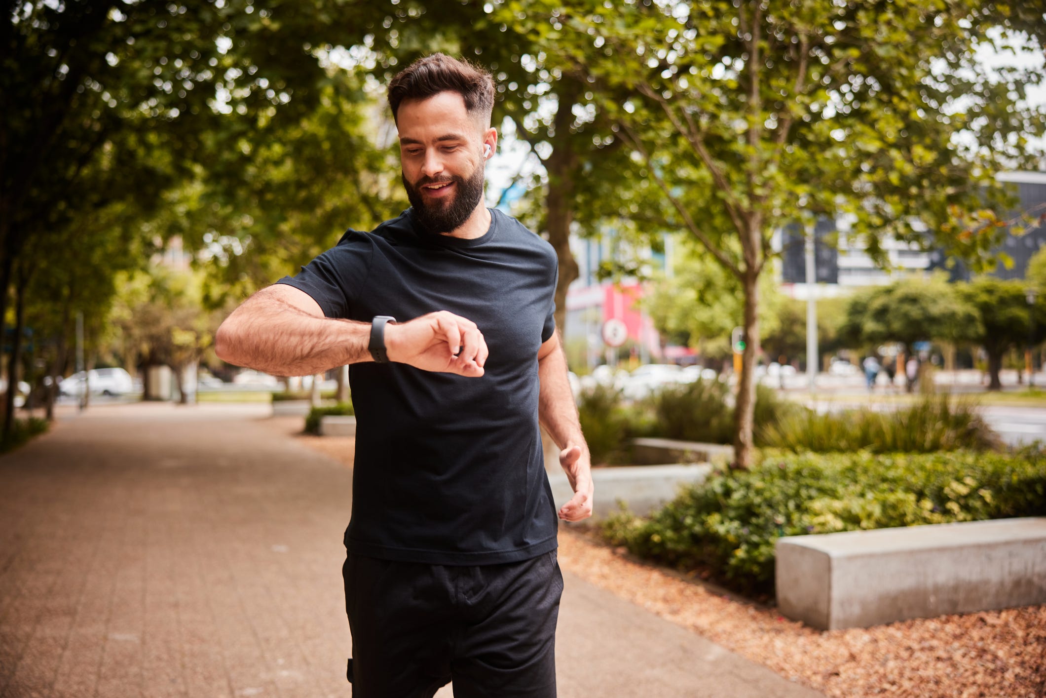 smiling man checking his fitness tracker during a park run