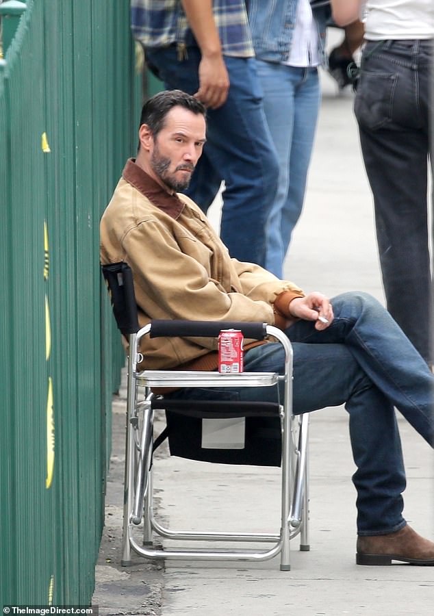 Reeves sat cross-legged on a foldable chair with a lit cigarette in hand and a can of the refreshing beverage placed by his side