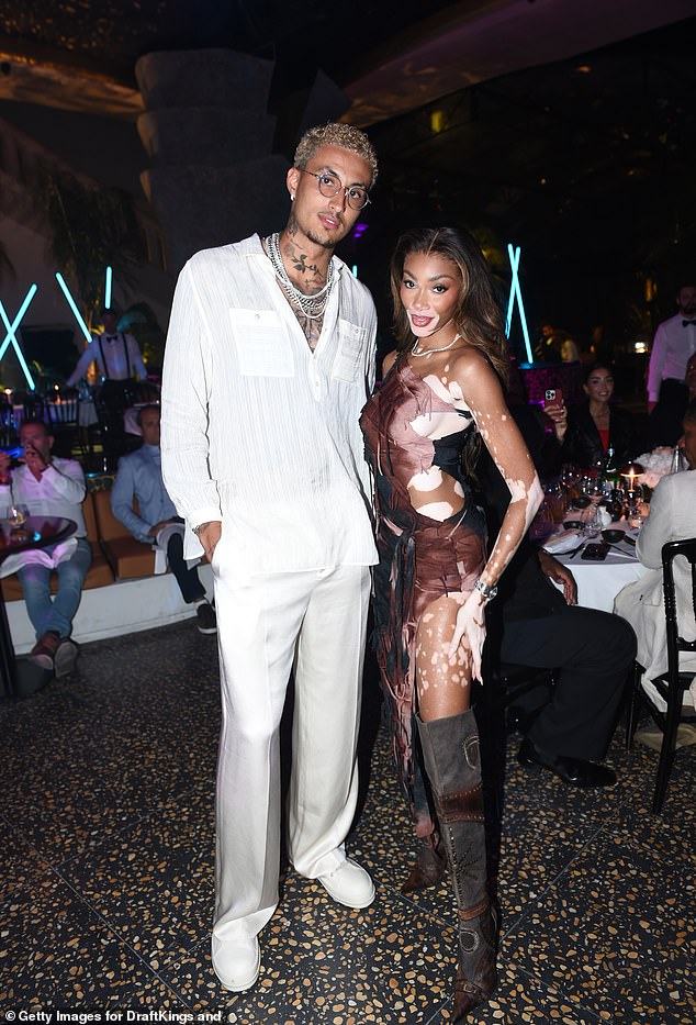 Winnie Harlow put her incredible figure in a racy cutaway dress and thigh high boots as she cuddled up to boyfriend Kyle Kuzma at the DraftKings x h.wood Media Dinner in Cannes