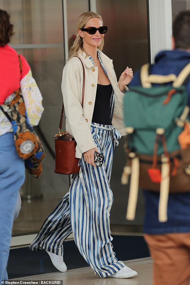 Cara's famous sister Poppy, 38, looked French-chic in blue and white satin trousers and stylish white trainers