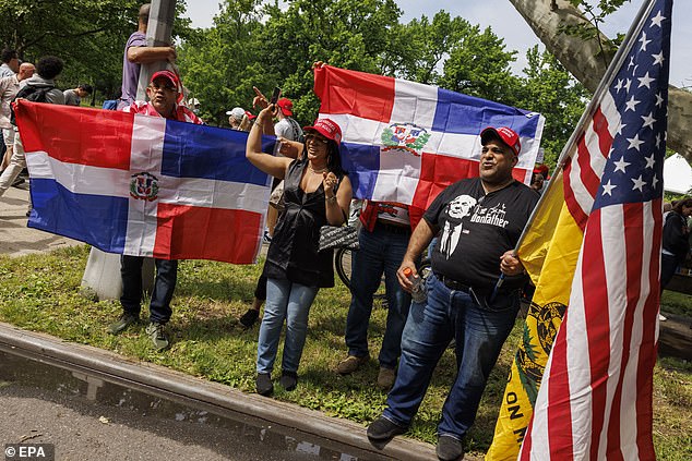 People with Dominican Republic and US flags chant while waiting in line to attend a rally for former US President Donald Trump at Crotona Park in the Bronx borough of New York