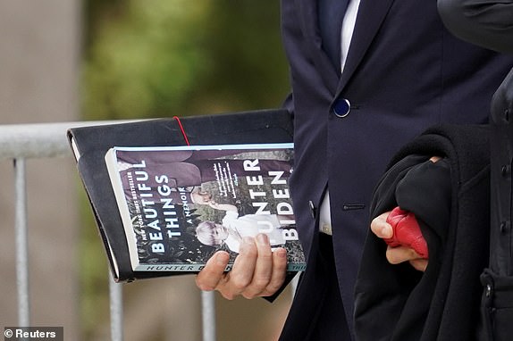 Hunter Biden, son of U.S. President Joe Biden, holds a copy of his memoir "Beautiful Things" as he and his wife Melissa Cohen Biden depart the federal court during his trial on criminal gun charges, in Wilmington, Delaware, U.S., June 5, 2024. REUTERS/Kevin Lamarque