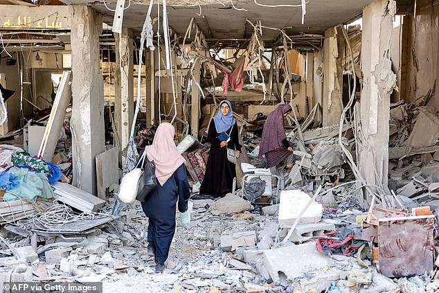 Women search the rubble of a destroyed dress shop in a residential building hit by Israeli bombardment, in the Daraj neighbourhood in Gaza City on June 14, 2024