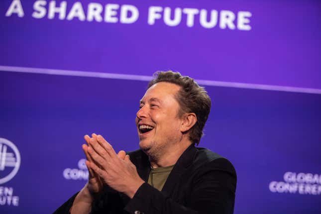 Elon Musk juntando sus manos y sonriendo