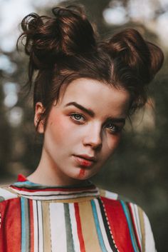 a young woman with red lipstick on her face and hair in top knoted buns