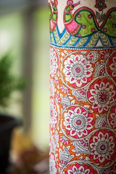 an ornately decorated vase sitting on top of a table next to a potted plant