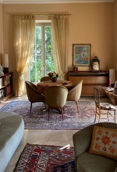 a living room filled with furniture next to a window covered in curtains and drapes