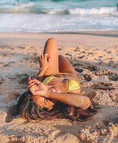 a woman laying on top of a sandy beach