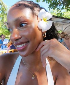 a woman with a flower in her hair smiles at the camera as she poses for a photo