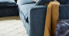 a blue couch with pillows on top of it and a blanket draped over the back